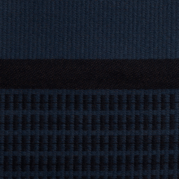 Close-up of the dark blue Danish woven wool fabric from Kjellerup Væveri, featuring a distinctive checkered pattern. The fabric showcases a blend of blue tones, reflecting the exquisite craftsmanship and refined texture characteristic of Kjellerup Væveri's designs, used in the Kelly Rutherford x August Sandgren Limited Edition Collection.